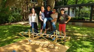 Secondary school pupils standing in front of a small wooden bridge in the gardens of King's Buildings Campus