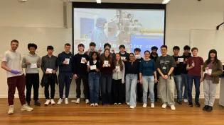 Secondary school pupils assembled in the front of a lectutre theatre holding summer school certificates