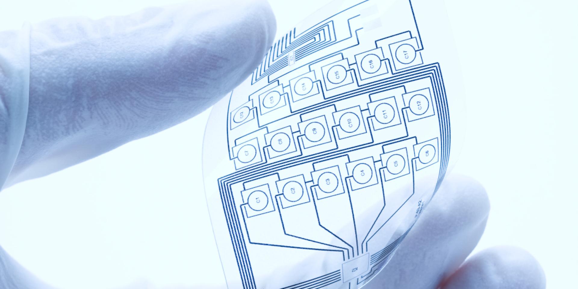 flexible electronnics gently held between the fingers of a gloved hand