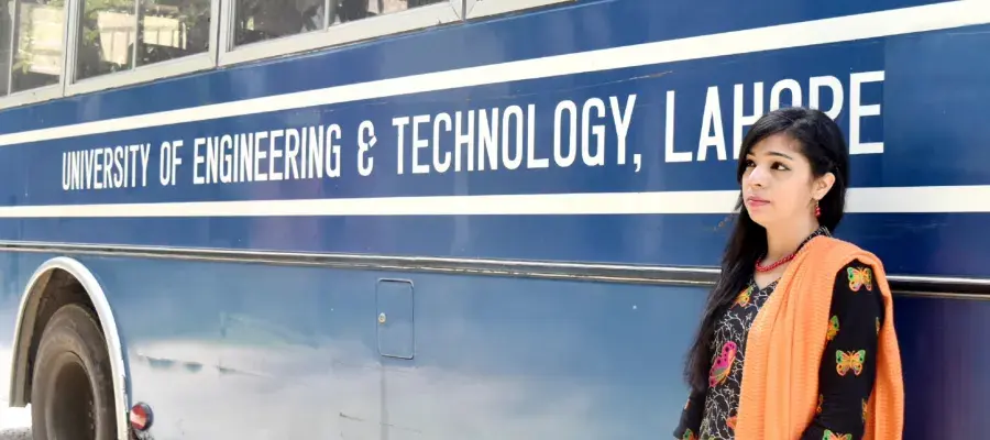 Anam standing beide a blue bus with the words "University of Engineering and Technology, Lahore" written in white