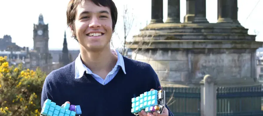 Lalit Mistry holding his ergonomic keyboard design on top of Calton Hill