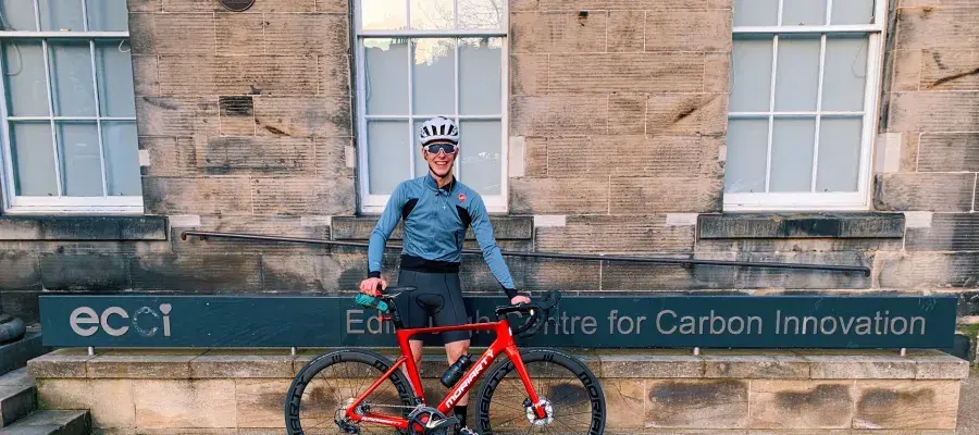 Louis Moore standing beside his road bike beside the Edinburgh Centre for Carbon Innovation