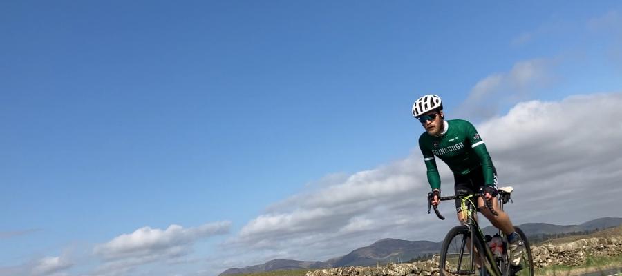 Peter Hicks cycling their road bike with blue sky in the background