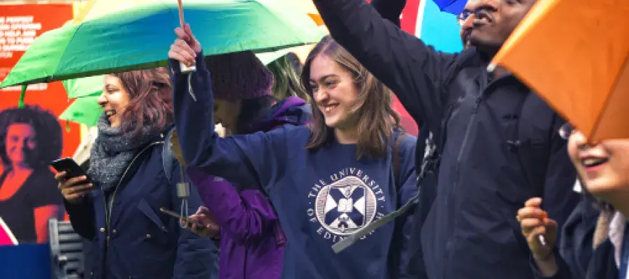 Students laughing in the rain, under umbrellas at Welcome Week