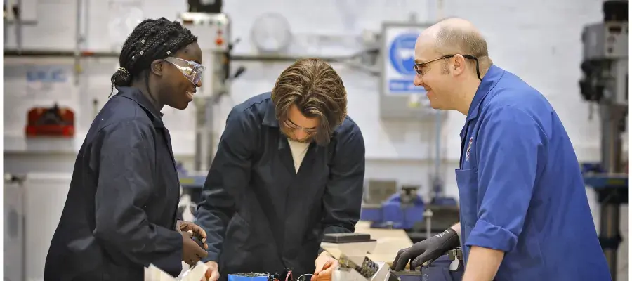 Two undergraduate students and a technician in a mechanical lab.