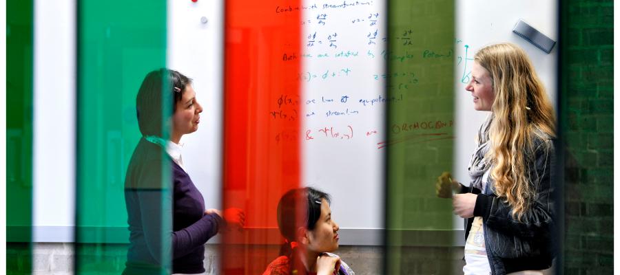 Three female students at the whiteboard