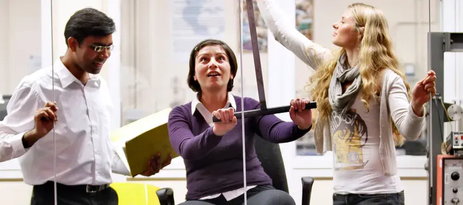 Mechanical engineering students smiling while working in a mechanical engineering workshop
