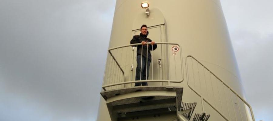 Rhodri standing beside a giant wind turbine (cropped for card)