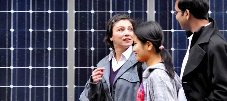 Engineering students talking while they walk past solar panels