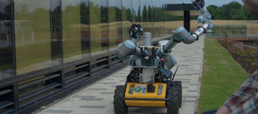 A robot with wheels and arms outside the National Robotarium centre at Heriot Watt University