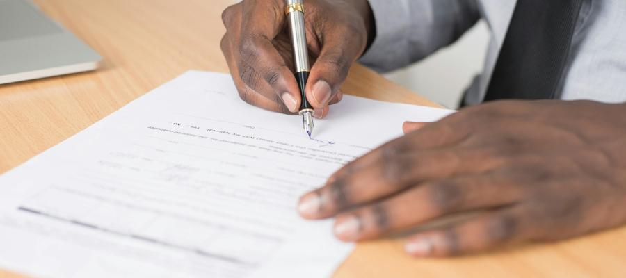 Person signing an application form with a pen