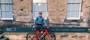 Louis Moore standing beside his road bike beside the Edinburgh Centre for Carbon Innovation