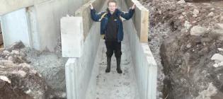 Tom Corlett standing inside an unfinished concrete slurry channel on a farm