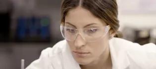 an engineering masters student in the laboratory wearing protective glasses and lab coat