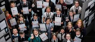 group of primary school children holding primary engineer awards and looking up to camera