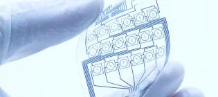 flexible electronnics gently held between the fingers of a gloved hand