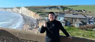 Maoqing Zhi standing in front of seaside scene with beach and cliffs in the distance