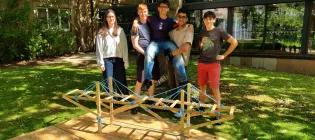 Seondary school pupils standing in front of a small wooden bridge outside the School of Engineering
