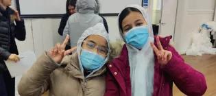 Primary School children wearing clean room safery clothing giving peace signs in front of a lecture theatre screen