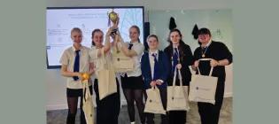 6 secondary school pupils in uniform holding aloft their drone challenge trophy in a lecture theatre