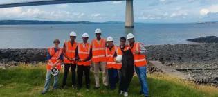 A group of secondary school pupils standing in front of the Queensferry Crossing road bridge by the RIver Forth