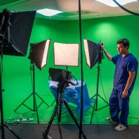 a person in medical dress videoing a table with a green screen background