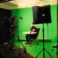 A person at a table on a green screen background