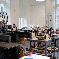 Close up of a 3D printer with a workshop in the background