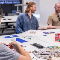 photo of two people talking in a sewing workshop while one person sews