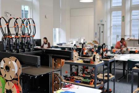 Close up of a 3D printer with a workshop in the background