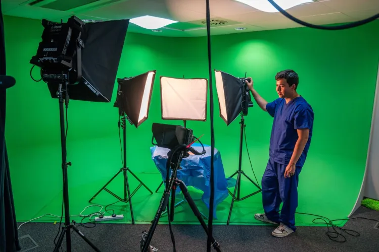 a person in medical dress videoing a table with a green screen background