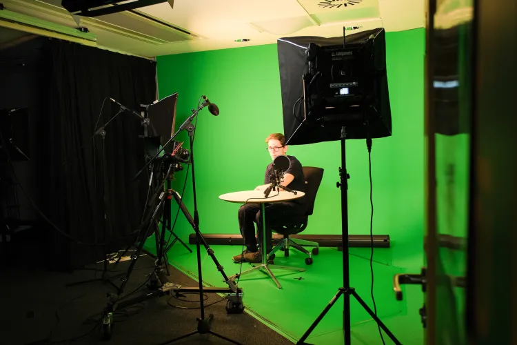 A person at a table on a green screen background
