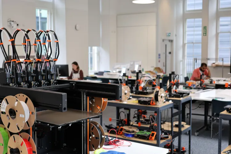 Close up of a 3D printer with a workshop in the background