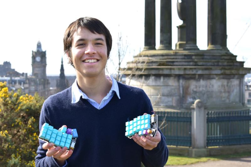 Lalit Mistry holding his ergonomic keyboard design on top of Calton Hill