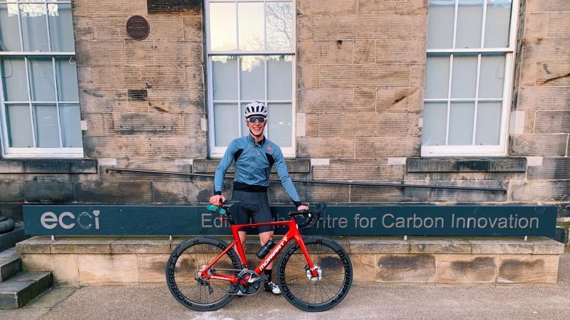 Louis Moore standing beside his road bike beside the Edinburgh Centre for Carbon Innovation