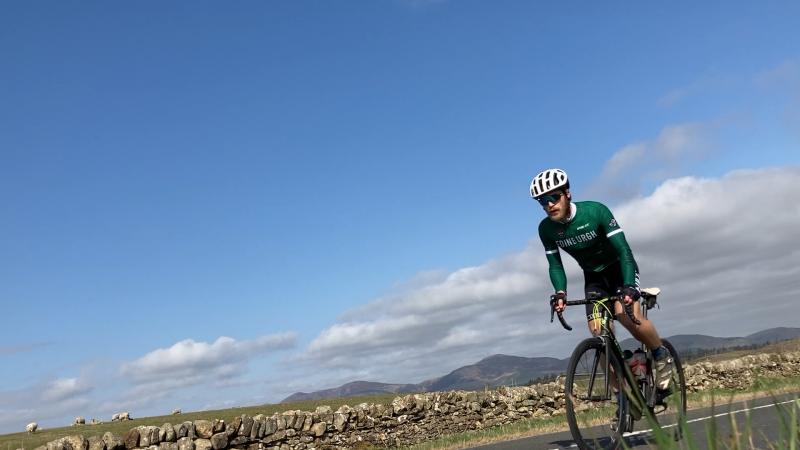 Peter Hicks cycling their road bike with blue sky in the background