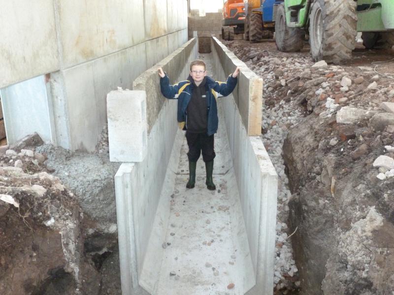Tom Corlett standing inside an unfinished concrete slurry channel on a farm