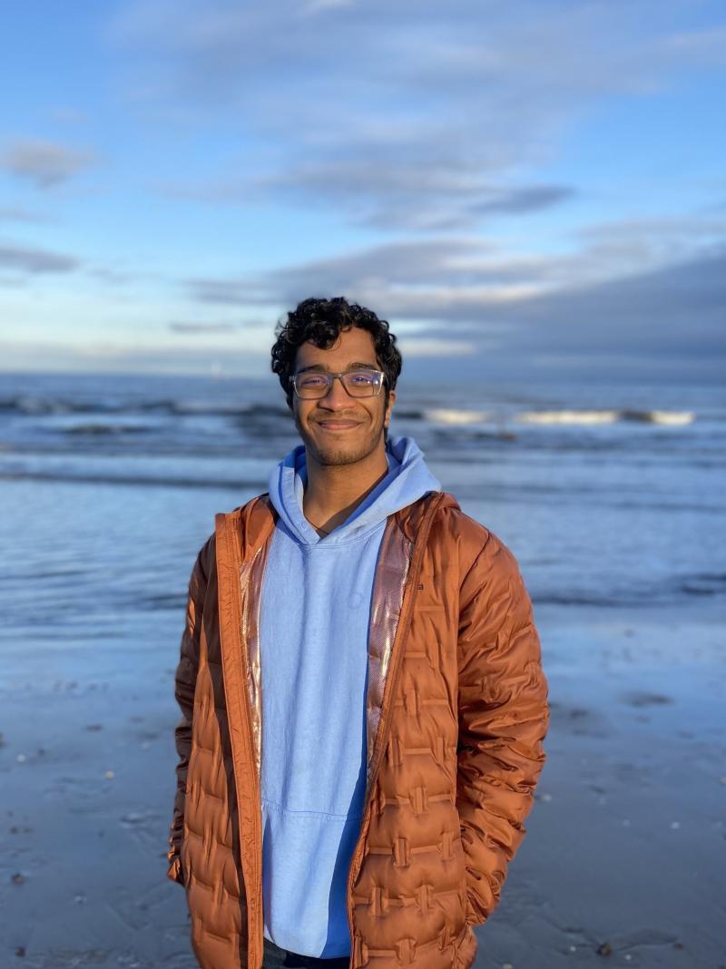 Mukhil Ramesh standing on a beach with sea and waves in the background