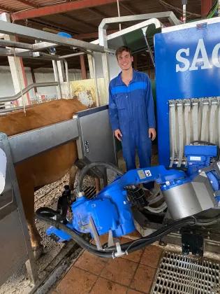 Rodrigo Corner standing beside a milking machine on a dairy farm