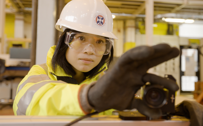 Postgraduate taught masters student wearing protective clothing, safety helmet and goggles in a laboratory in the School of Engineering