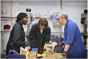 Two undergraduate students and a technician in a mechanical lab.