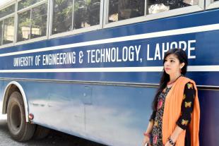 Anam standing beide a blue bus with the words "University of Engineering and Technology, Lahore" written in white