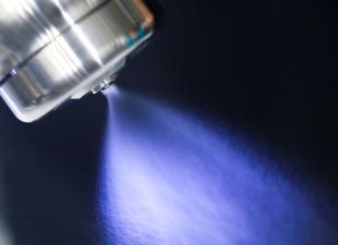 image of downward spray emitted from nozzle of can at top left, with black background