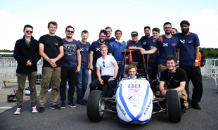 Edinburgh University Formula Student team photo, students standing behind car on race track