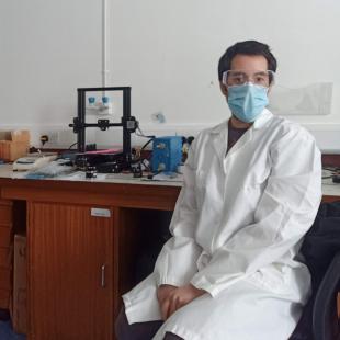 Francisco Diaz Sanchez wearing a lab coar and face mask, sitting in a research laboratory