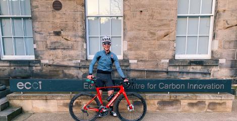 Louis Moore standing beside his road bike beside the Edinburgh Centre for Carbon Innovation